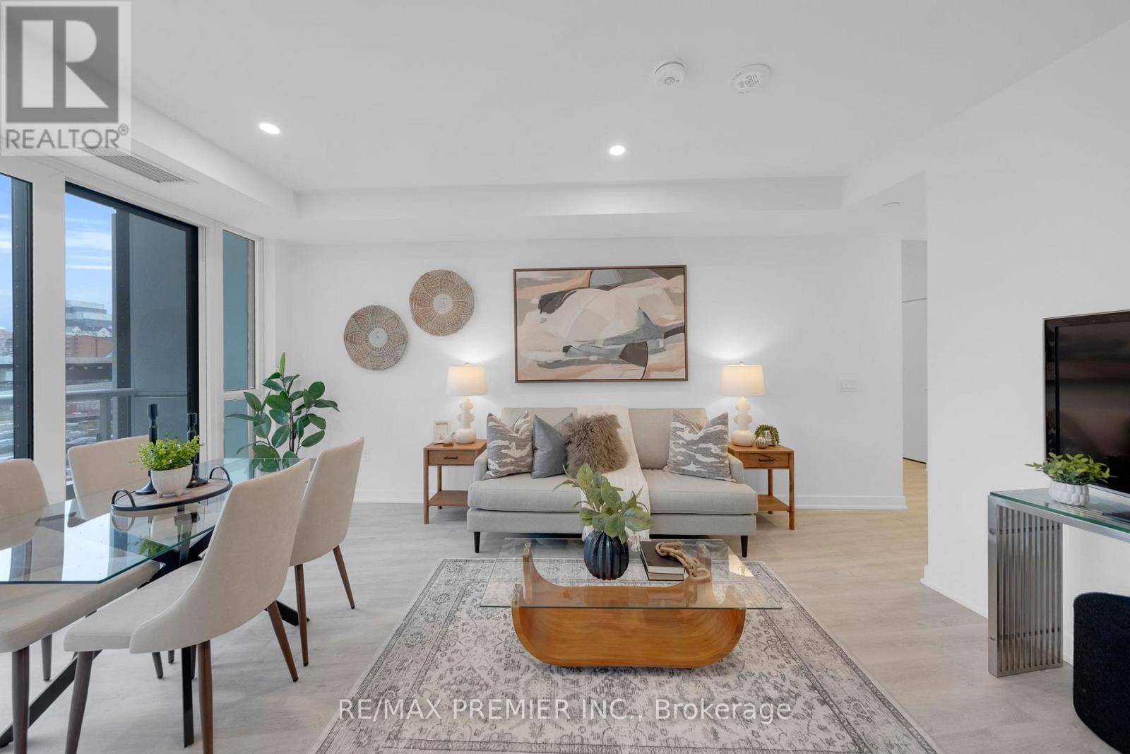A modern living room with a glass table and a grey sofa.