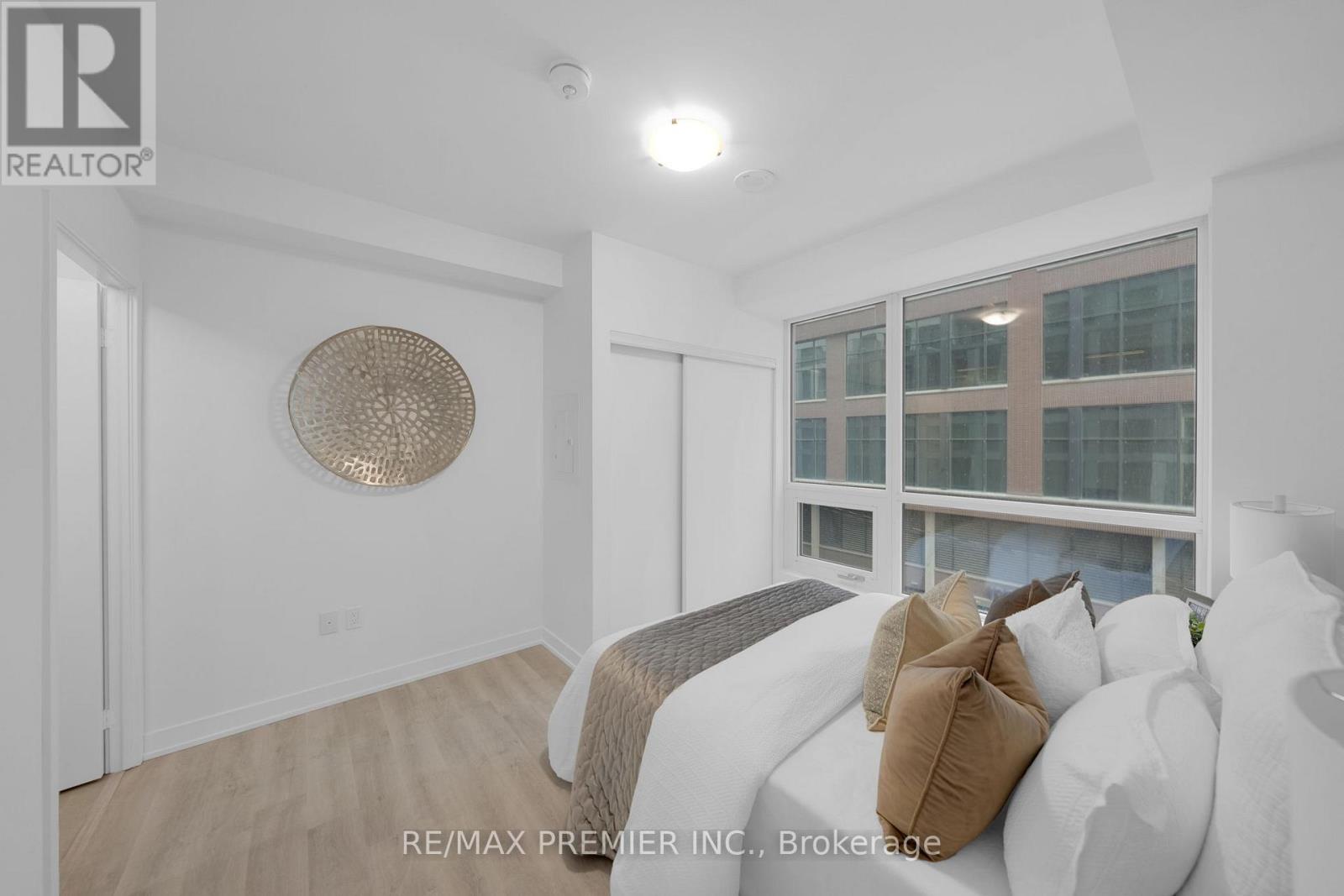 A bedroom with a bed and a window overlooking a building.