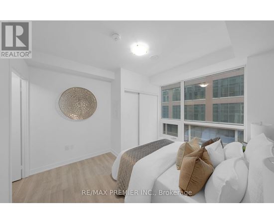 A bedroom with a bed and a window overlooking a building.