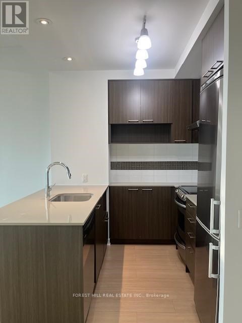A modern kitchen with dark wood cabinets and stainless steel appliances.
