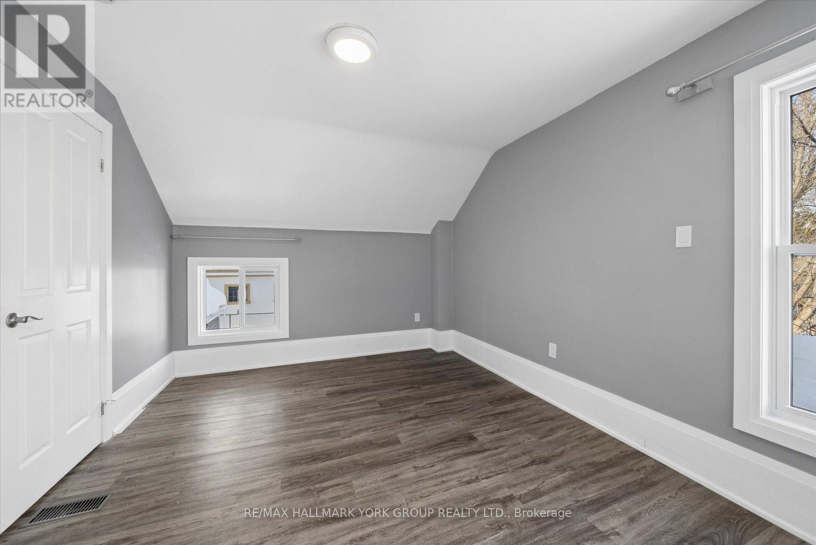 A room with a white door and a window with a view of trees.