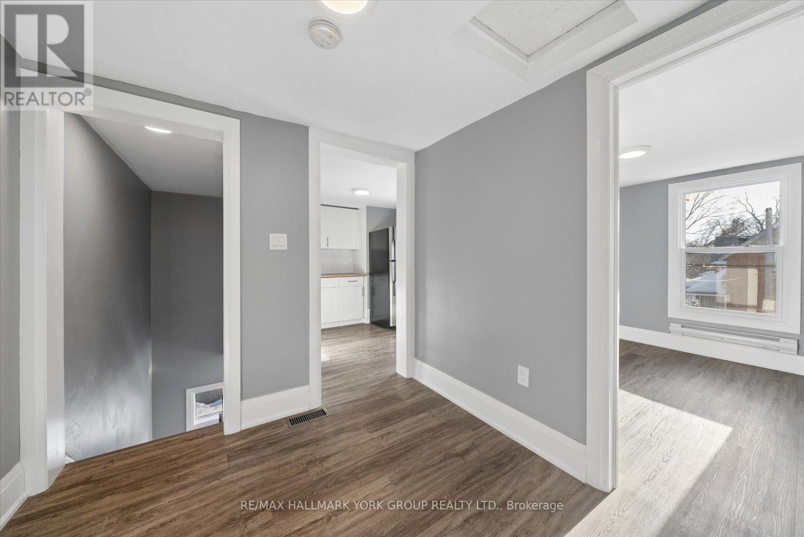 A spacious, empty room with wood flooring and white walls.
