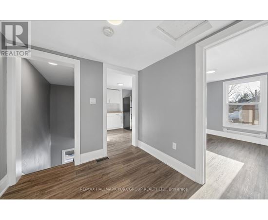 A spacious, empty room with wood flooring and white walls.