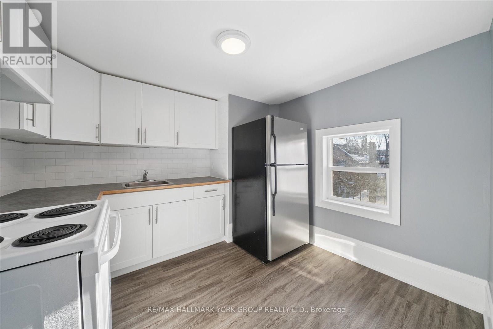 A kitchen with white cabinets and a black refrigerator.
