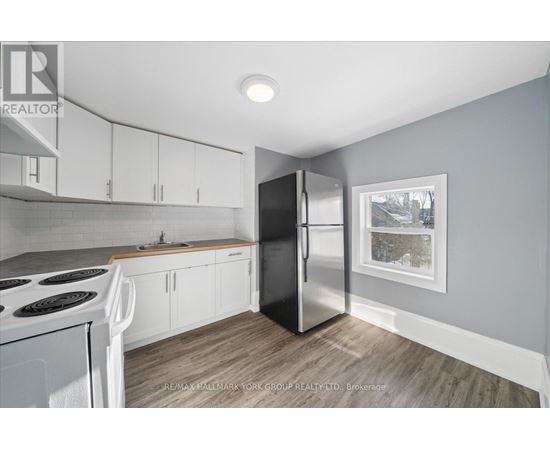A kitchen with white cabinets and a black refrigerator.
