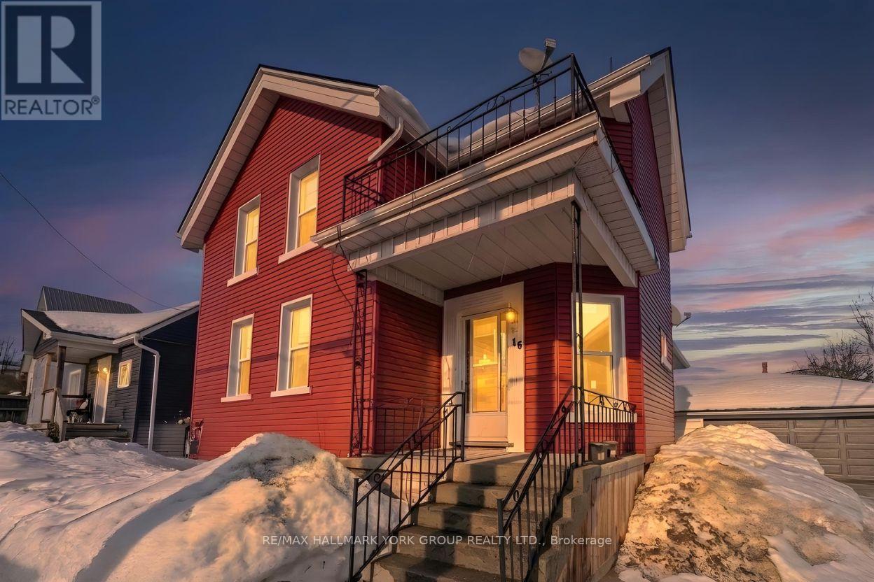 A red house with a balcony and stairs leading to the front door.