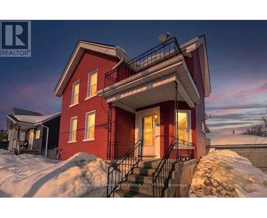 A red house with a balcony and stairs leading to the front door.