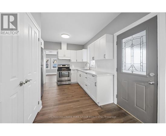 A kitchen with white cabinets and a grey door.
