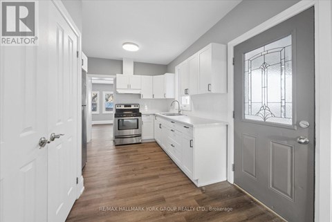 A kitchen with white cabinets and a grey door.