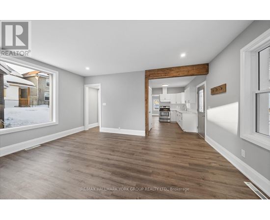 A spacious room with wooden flooring and white walls.