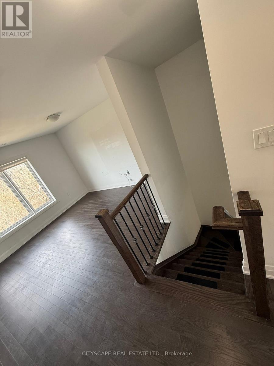 A wooden staircase with a black tread leads up to a window.