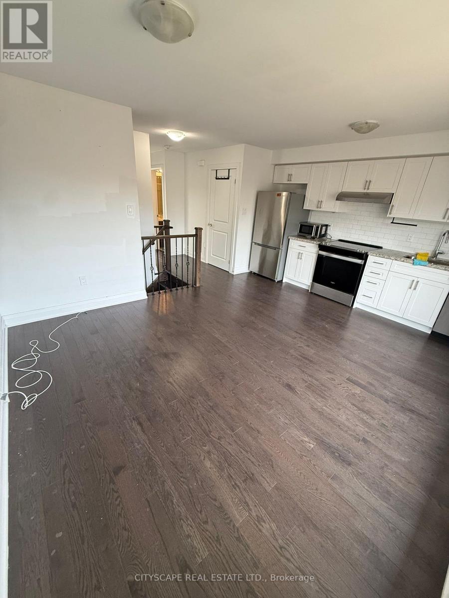 A kitchen with white cabinets and a wooden floor.