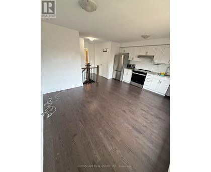 A kitchen with white cabinets and a wooden floor.