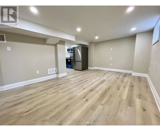 A spacious room with wooden flooring and a kitchenette in the corner.