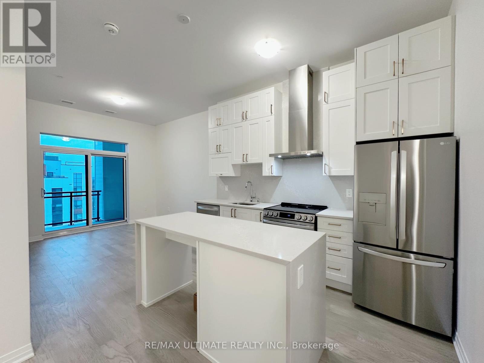 A white kitchen with a stainless steel refrigerator and a stove top oven.