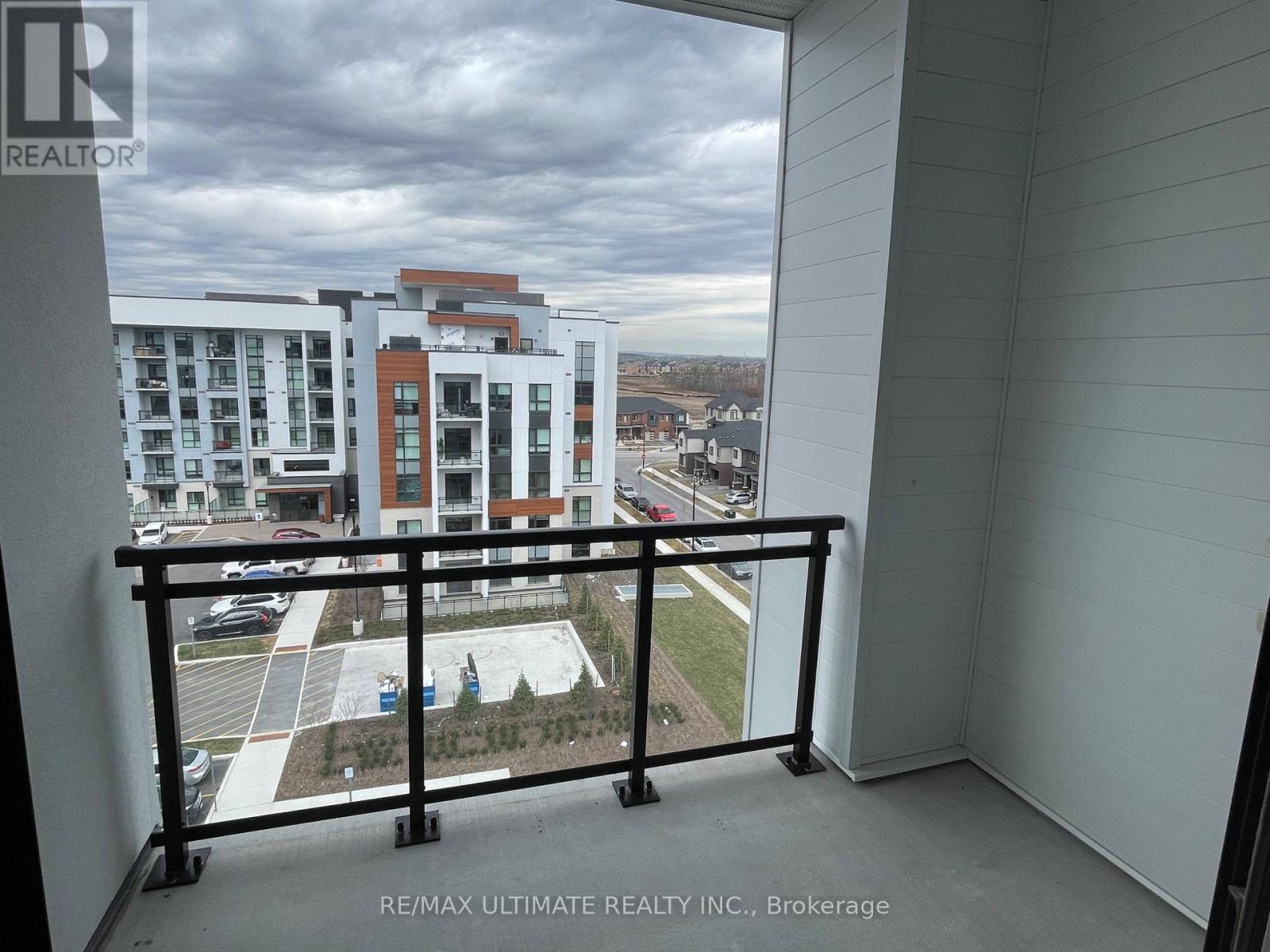 A balcony with a view of a parking lot and buildings.
