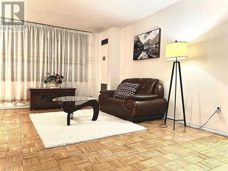 A living room with a brown leather couch, a glass coffee table, and a floor lamp.