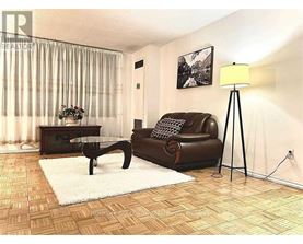 A living room with a brown leather couch, a glass coffee table, and a floor lamp.