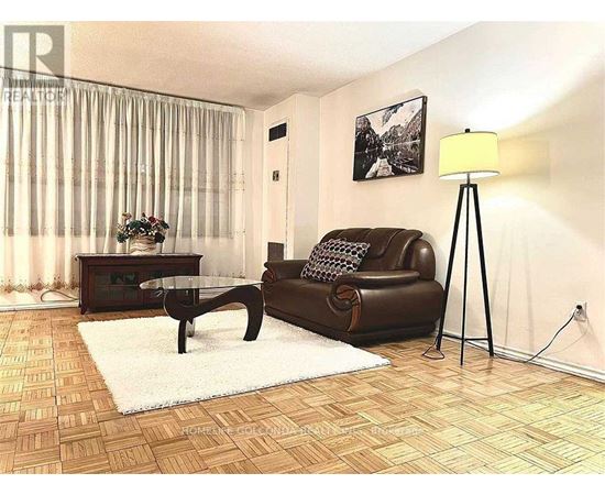 A living room with a brown leather couch, a glass coffee table, and a floor lamp.