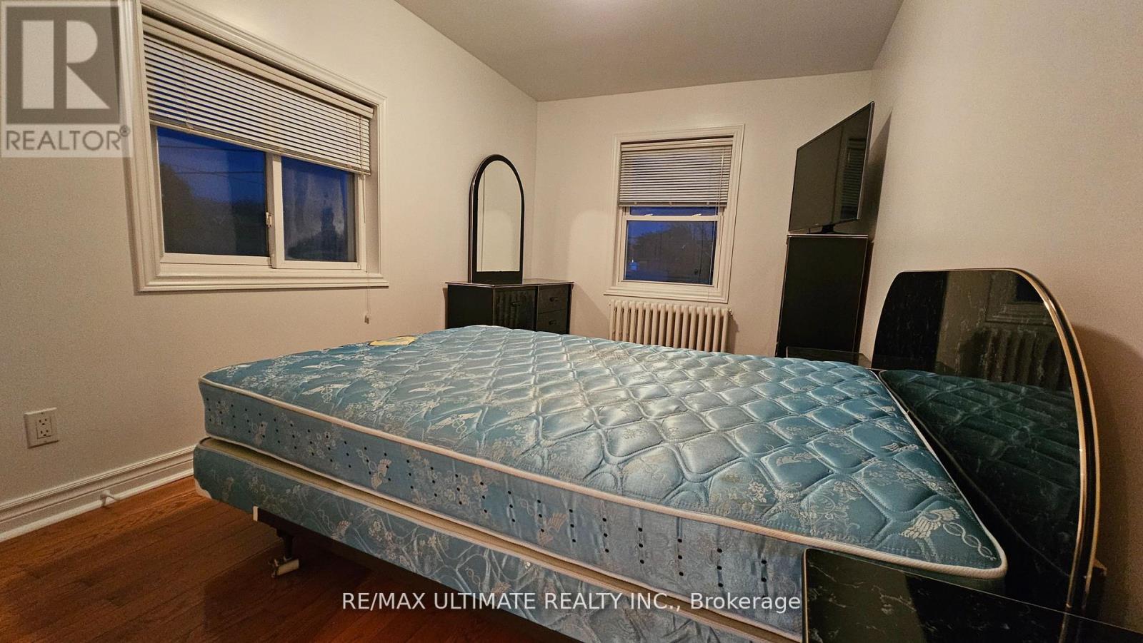 A bedroom with a bed, dresser, and mirror.