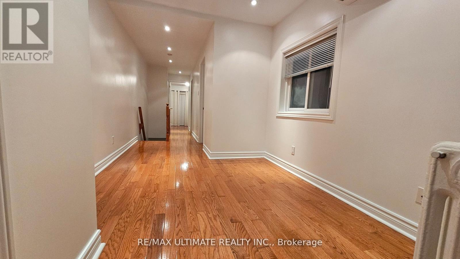A long hallway with wood floors and white walls.