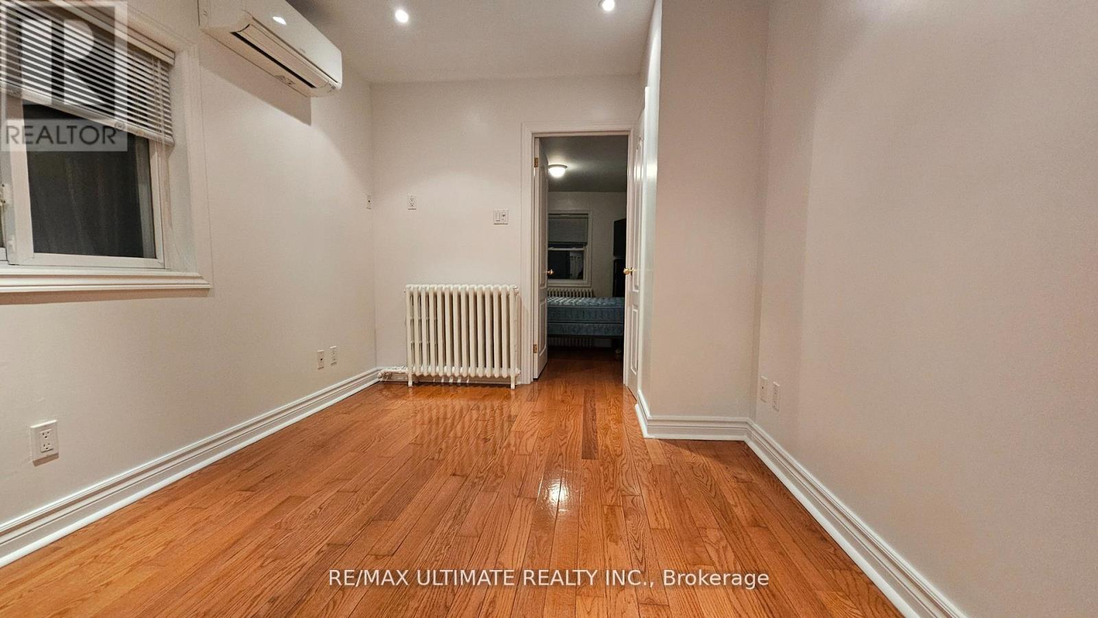 A room with wooden floors and a window with blinds.