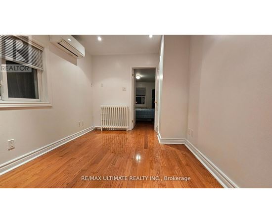 A room with wooden floors and a window with blinds.
