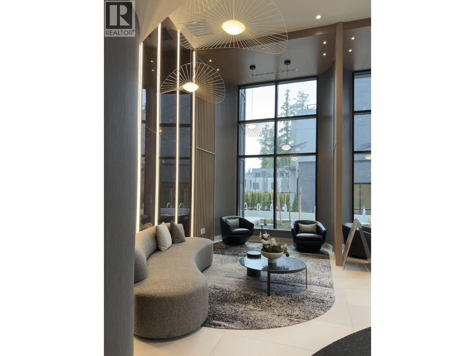 A modern living room with a large window and a grey couch.