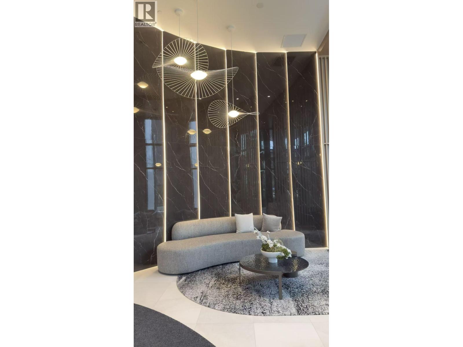 A modern living room with a grey sofa and a glass table.
