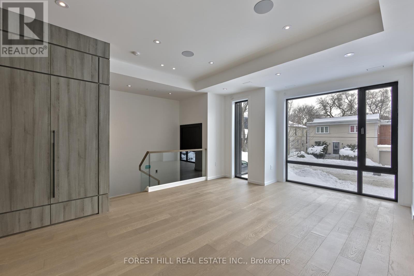 A spacious room with a wooden floor and a large window overlooking a snowy landscape.