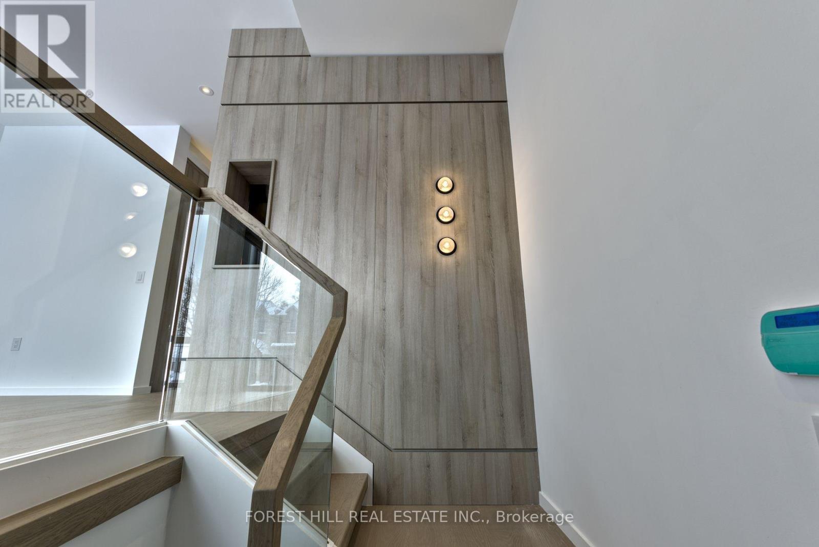 A staircase with a wooden wall and a glass railing.