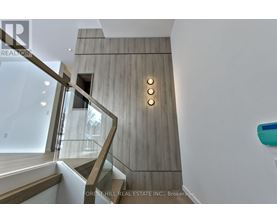 A staircase with a wooden wall and a glass railing.