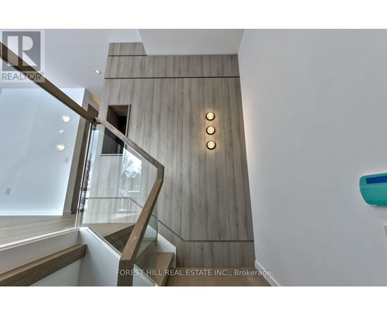 A staircase with a wooden wall and a glass railing.