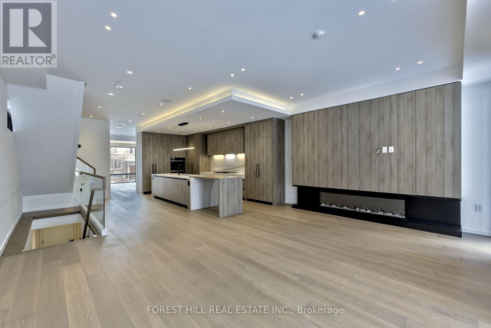 A spacious living room with wood paneling and a fireplace.