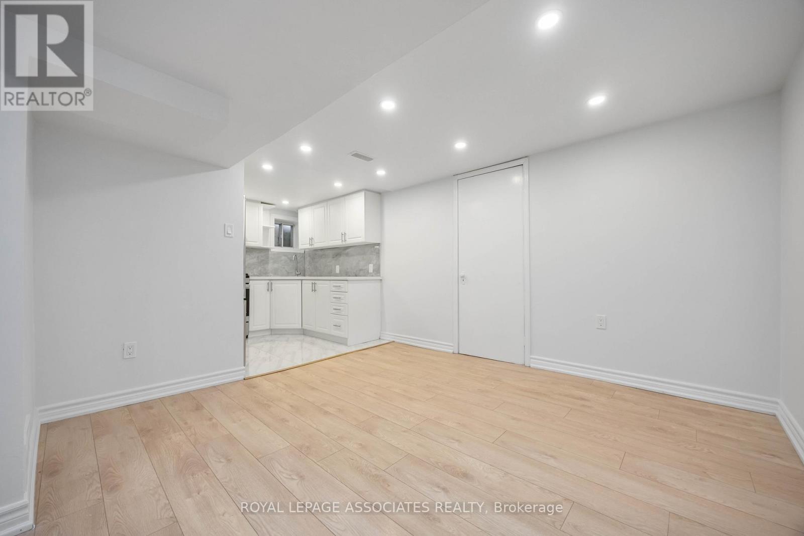 A spacious room with wooden flooring and white walls.