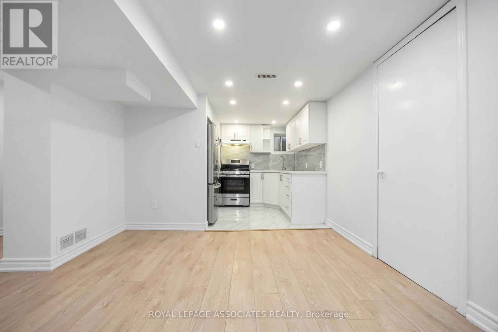 A spacious kitchen with white cabinets and a wooden floor.