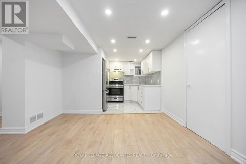 A spacious kitchen with white cabinets and a wooden floor.