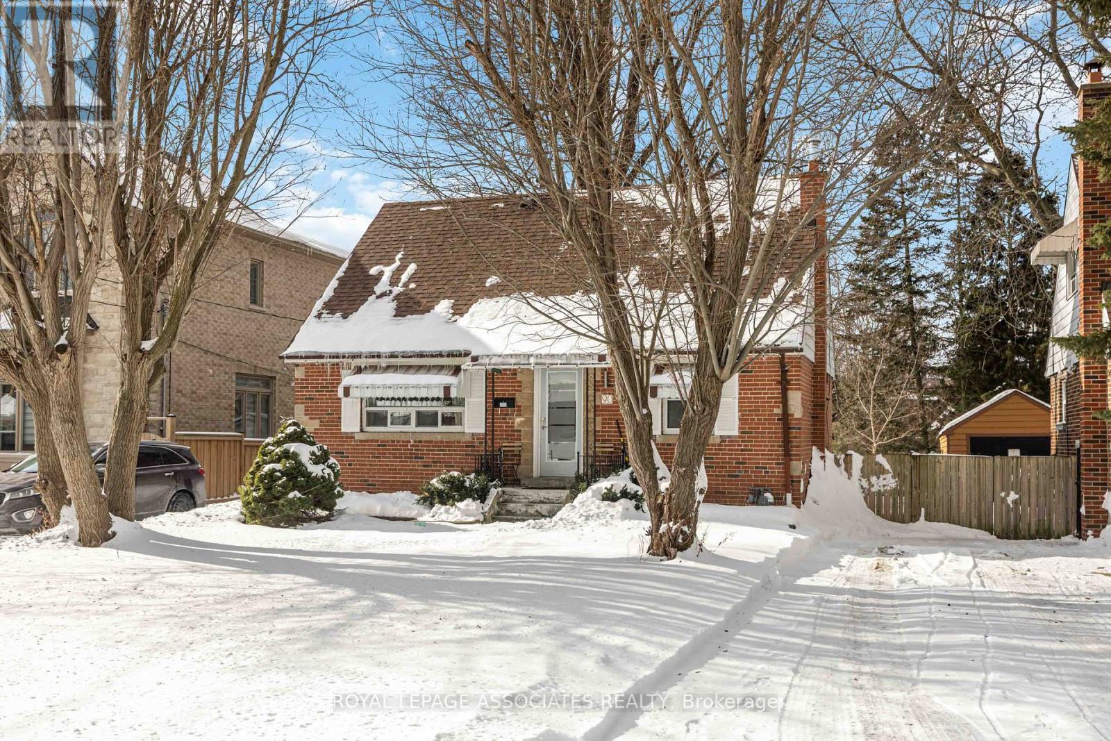 A house with a snow-covered front yard and bare trees.