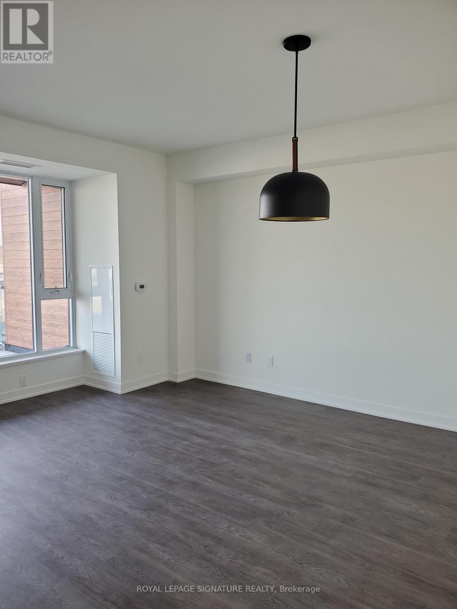 A room with a grey floor and a black pendant light hanging from the ceiling.