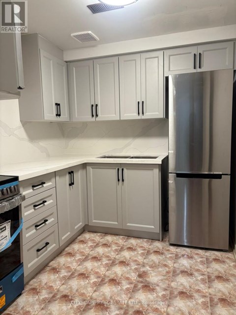 A kitchen with a stainless steel refrigerator and cabinets.