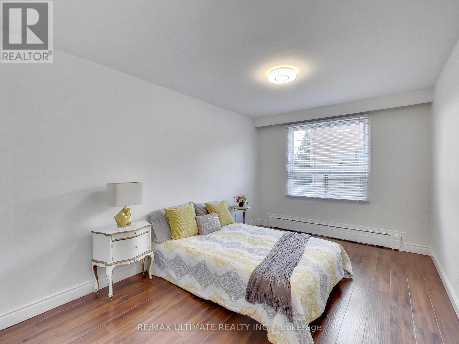 A bedroom with a bed, nightstand, and window.