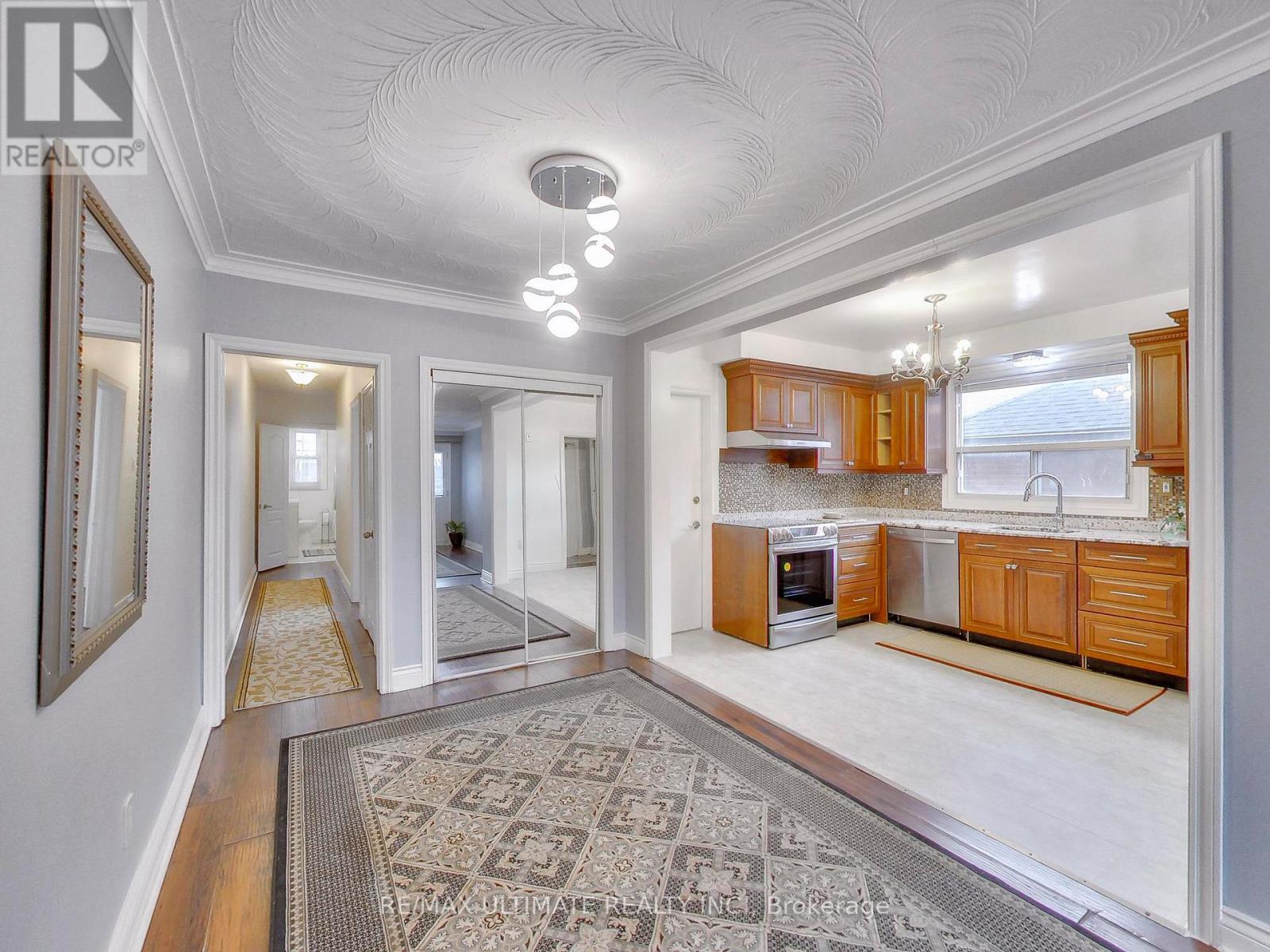 A well-lit, spacious kitchen and dining area with wooden cabinets and a patterned rug on the floor.