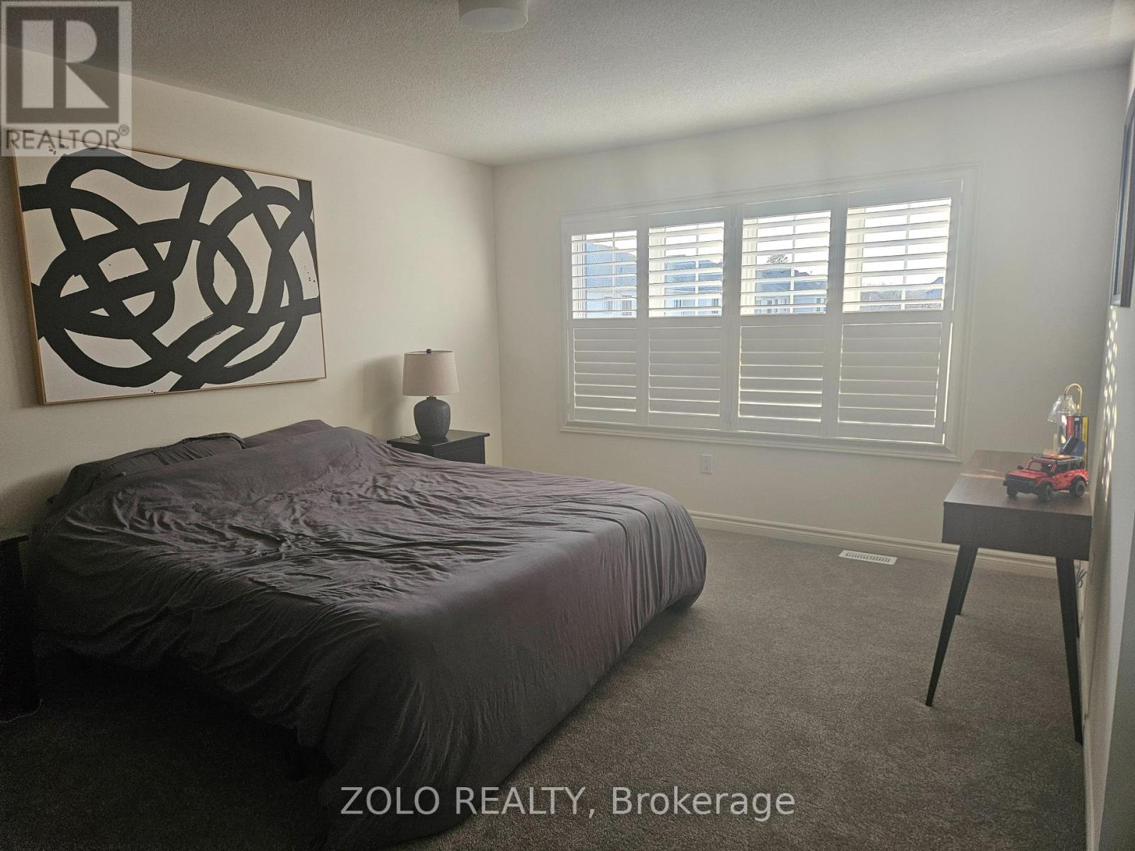 A bedroom with a large bed and a large abstract painting on the wall.