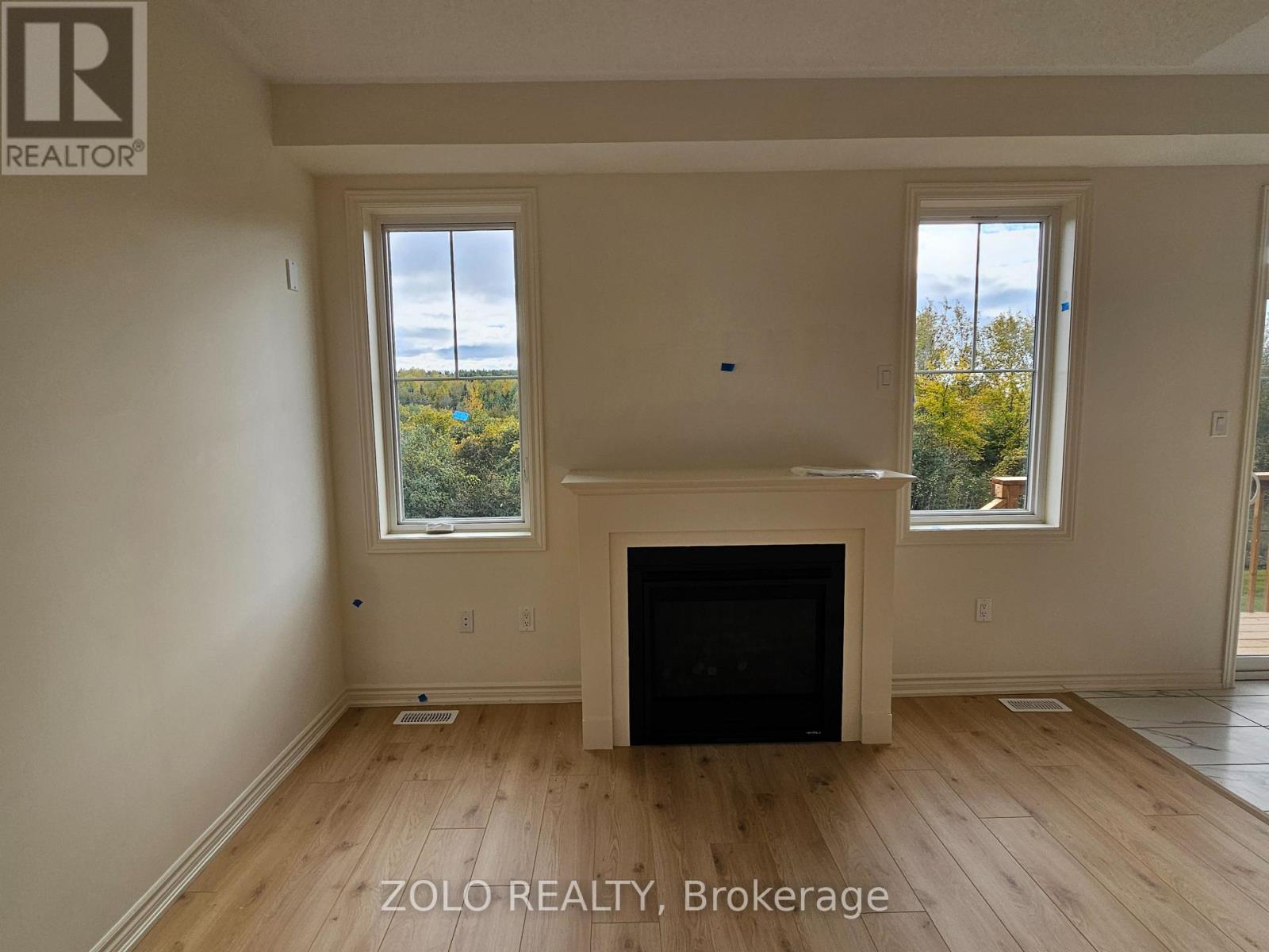 A living room with a fireplace and two windows.