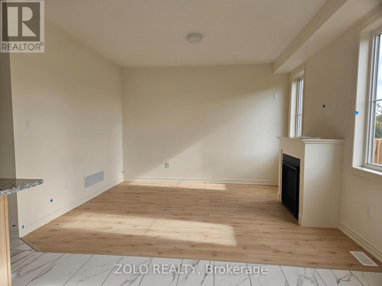 A spacious room with wooden flooring and a fireplace.