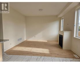 A spacious room with wooden flooring and a fireplace.