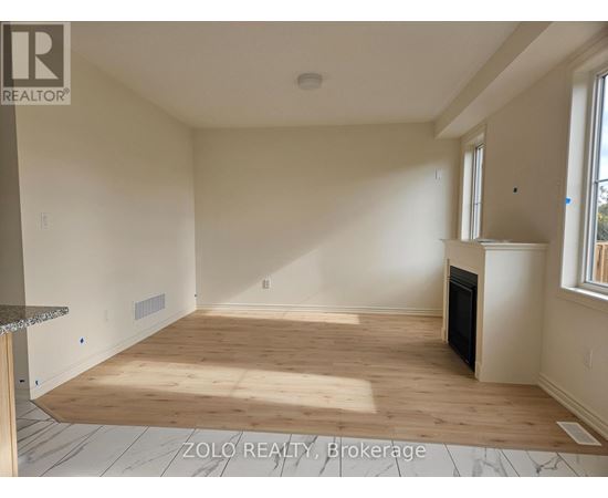 A spacious room with wooden flooring and a fireplace.
