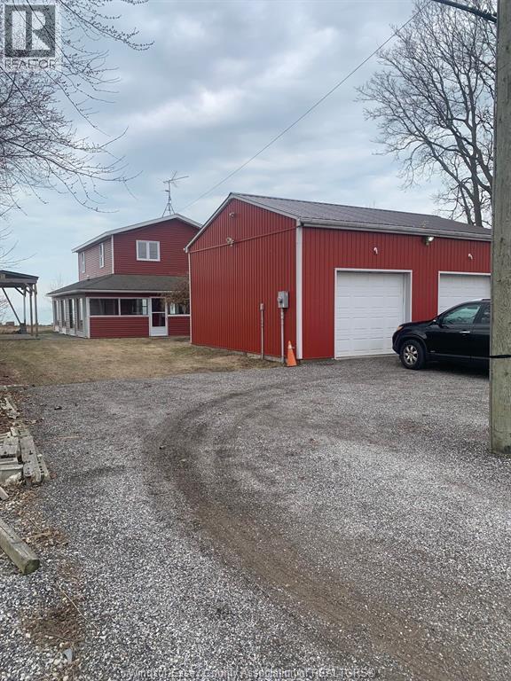 A red barn with a white door and a black car parked in front.