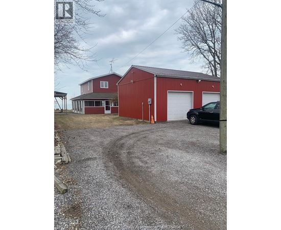 A red barn with a white door and a black car parked in front.