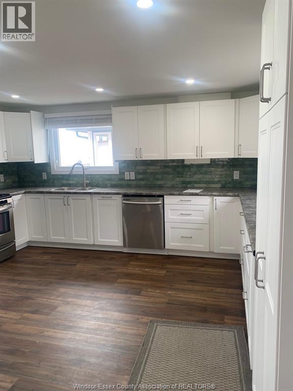A kitchen with white cabinets and a wooden floor.
